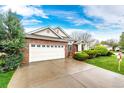 A brick home with a two-car garage and extra wide driveway, complimented by a beautiful, green, manicured lawn at 3802 Lee Cir, Wheat Ridge, CO 80033