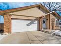 Attached garage with white door and brick exterior at 7338 S Yukon Ct, Littleton, CO 80128