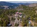 Aerial view of a cozy mountain cabin surrounded by lush trees and mountain views at 3945 Douglas Mountain Dr, Golden, CO 80403