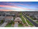 Wide aerial view of the neighborhood with a house with two car garage at sunset at 3480 Mount Powell Dr, Broomfield, CO 80023