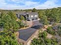 A modern two-story home with a three-car garage nestled in a wooded area with a paved driveway at 922 W Wolfensberger Rd, Castle Rock, CO 80109