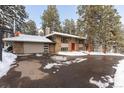 Wide shot of the home with a two-car garage, basketball hoop, and snow-covered yard at 27837 Whirlaway Trl, Evergreen, CO 80439