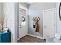 Bright entryway with a decorative front door, coat rack, wood floors, and light gray walls with wallpaper accent at 12278 Stone Timber Ct, Parker, CO 80134