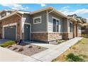 Exterior corner of a gray home with stone accents, a gray garage door, and a gray front door with landscaping at 12278 Stone Timber Ct, Parker, CO 80134