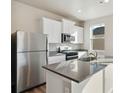 Kitchen showcasing stainless steel appliances, grey countertops, white cabinetry, and a kitchen island at 3036 Oxley St, Strasburg, CO 80136