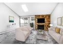 Living room with stone fireplace, modern furnishings, and sliding doors to the balcony at 381 S Ames St # E305, Lakewood, CO 80226