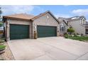 Charming brick home featuring a three-car garage, manicured lawn, and decorative exterior details at 2190 Coyote Creek Dr, Fort Lupton, CO 80621