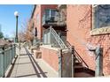 Brick condo exterior shows balcony, metal staircase, gray trim, and street lamp at 1440 Little Raven St # 107, Denver, CO 80202