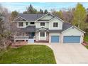 Charming two-story home with a lush lawn, blue garage doors, and inviting curb appeal at 7307 Pine Forest Ln, Parker, CO 80134