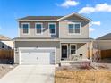 Two-story home featuring gray siding, a two-car garage, and a welcoming front porch at 2489 Alto St, Fort Lupton, CO 80621