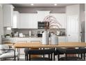 Bright kitchen with white cabinets, granite countertops, and a decorative dining table at 2489 Alto St, Fort Lupton, CO 80621