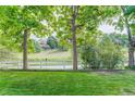 A serene backyard featuring a lush green lawn and a white picket fence with mature trees and landscape at 10032 Astoria Ct, Lone Tree, CO 80124