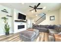 Inviting living room featuring a cozy fireplace, stylish ceiling fan, floating shelves, and comfortable gray sectional at 3734 Makley Cir, Castle Rock, CO 80104