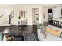 Bright living area showcasing staircase, dark wood floors, and a stylish black and white rug at 10465 Evansville Cir, Parker, CO 80134