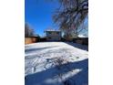Large, snow covered backyard featuring a tall fence and mature trees in a quiet neighborhood at 857 S Leyden St, Denver, CO 80224