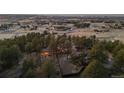 A unique property featuring a sprawling home, mature trees, and city views in the background at dusk at 7076 Inspiration Dr, Parker, CO 80138