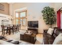 Spacious living room with high ceilings, large windows, hardwood floors, a leather sofa, and a decorative tree at 13330 York Way, Thornton, CO 80241