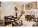Open-concept living area featuring hardwood floors, a staircase, comfortable leather seating, and elegant chandelier at 13330 York Way, Thornton, CO 80241