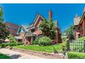 Quaint brick home showing a well-manicured lawn and garden, mature trees, and charming architectural details at 931 E 17Th Ave, Denver, CO 80218
