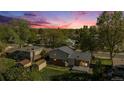 Aerial view of home nestled among mature trees and surrounded by lush green lawns at sunset at 9345 W Iowa Pl, Lakewood, CO 80232