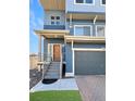 Close up of a modern two-story home's entrance with a brown front door and a gray front-facing garage at 17908 E 54Th Ave, Denver, CO 80249