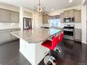Spacious kitchen with gray cabinets, granite counters, stainless steel appliances, and dark hardwood floors at 17908 E 54Th Ave, Denver, CO 80249