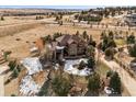 An aerial view shows this home with a red tile roof surrounded by an expansive, treed property in a rural setting at 5582 Twilight Way, Parker, CO 80134