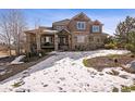 Charming home featuring a stone and stucco facade, covered porch, well-maintained lawn and snow-covered landscape at 5582 Twilight Way, Parker, CO 80134