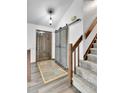 Inviting entryway with wood-look flooring, barn door, and a staircase leading to the upper level at 7796 S Marshall Ct, Littleton, CO 80128