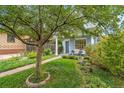 View of a light blue home with a cozy front porch, chairs, and landscaped yard with mature tree at 4508 W 34Th Ave, Denver, CO 80212