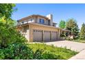 View of the home featuring a three-car garage and beautifully landscaped surroundings at 4800 E Cedar Ave, Denver, CO 80246