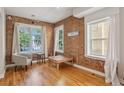 Bright living room featuring hardwood floors, exposed brick wall, and multiple windows at 1580 N Franklin St, Denver, CO 80218