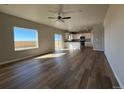 Bright, open living area with wood floors and a modern ceiling fan, flowing into the kitchen with white cabinetry at 48270 Shetland Dr, Bennett, CO 80102