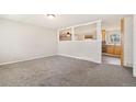 Bright living room featuring gray walls, neutral carpet, and a large cut-out wall looking into the kitchen at 3270 W 92Nd Pl, Westminster, CO 80031