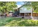 Spacious backyard featuring a well-maintained lawn, a fire pit, and an elevated deck with stairs leading down to the yard at 8063 S Otis Ct, Littleton, CO 80128
