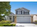 Charming two-story home featuring a covered porch, manicured lawn, and brick accents during daytime at 9200 W Indore Dr, Littleton, CO 80128