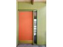 Close up of vibrant orange front door with vintage hardware and sidelight window at 5450 Mohawk Rd, Littleton, CO 80123