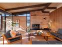 Inviting living room with brick fireplace, wood paneled walls, and beam ceiling at 5450 Mohawk Rd, Littleton, CO 80123