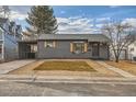 Well-maintained gray single story home featuring a gravel front yard and wood toned shutters, offering cozy curb appeal at 921 Meade St, Denver, CO 80204