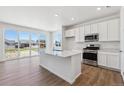 Bright kitchen features stainless steel appliances, center island with a sink, and sliding glass doors at 18961 E 96Th Pl, Commerce City, CO 80022