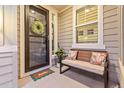 Inviting front porch with 'hello' door mat, wreath, bench with pillows, and a lovely potted plant at 17335 W 94Th Ave, Arvada, CO 80007