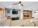 Cozy living room with a brick fireplace, wood mantle, modern ceiling fan, and comfortable seating at 10378 W Weaver Ave, Littleton, CO 80127