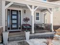 Charming covered porch with black door and potted plants at 27750 E Lakeview Dr, Aurora, CO 80016