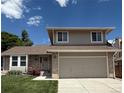 Inviting two-story home boasts a well-maintained lawn, brick accents, and attached two-car garage at 12089 W Burgundy Ave, Littleton, CO 80127