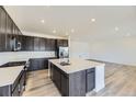 Open kitchen with dark cabinets, quartz countertops, large island, and stainless steel appliances at 24715 E Evans Dr, Aurora, CO 80018