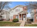 Traditional home with brick accents, white siding, well-manicured lawn, and inviting front porch at 10700 Kimblewyck Cir # 225, Northglenn, CO 80233