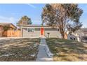 Gray house with orange door, solar panels, and fenced yard at 1765 S Irving St, Denver, CO 80219