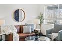 Cozy living room features a brown leather couch, round mirror, and ample natural light at 4842 Steele St, Denver, CO 80216