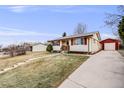 A well-maintained single-story home with red shutters, complemented by a detached garage and driveway at 1308 W 102Nd Ave, Northglenn, CO 80260