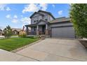 Beautiful gray home with a welcoming front porch and two-car garage, complemented by a green lawn at 8182 Grady Cir, Castle Rock, CO 80108